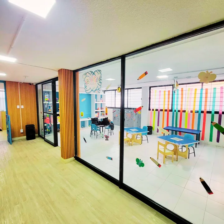 Salones con muros de cristal y mesas infantiles